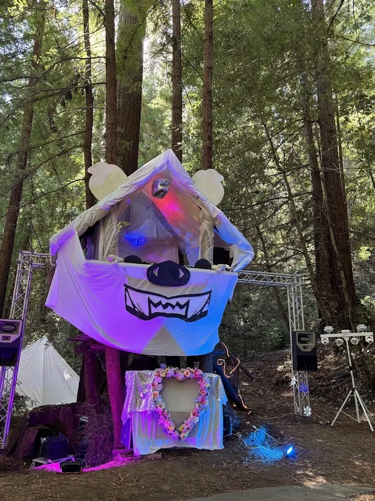 Polar Peak: a giant white polar bear head built around a treehouse DJ booth, lit pink and blue among the redwoods